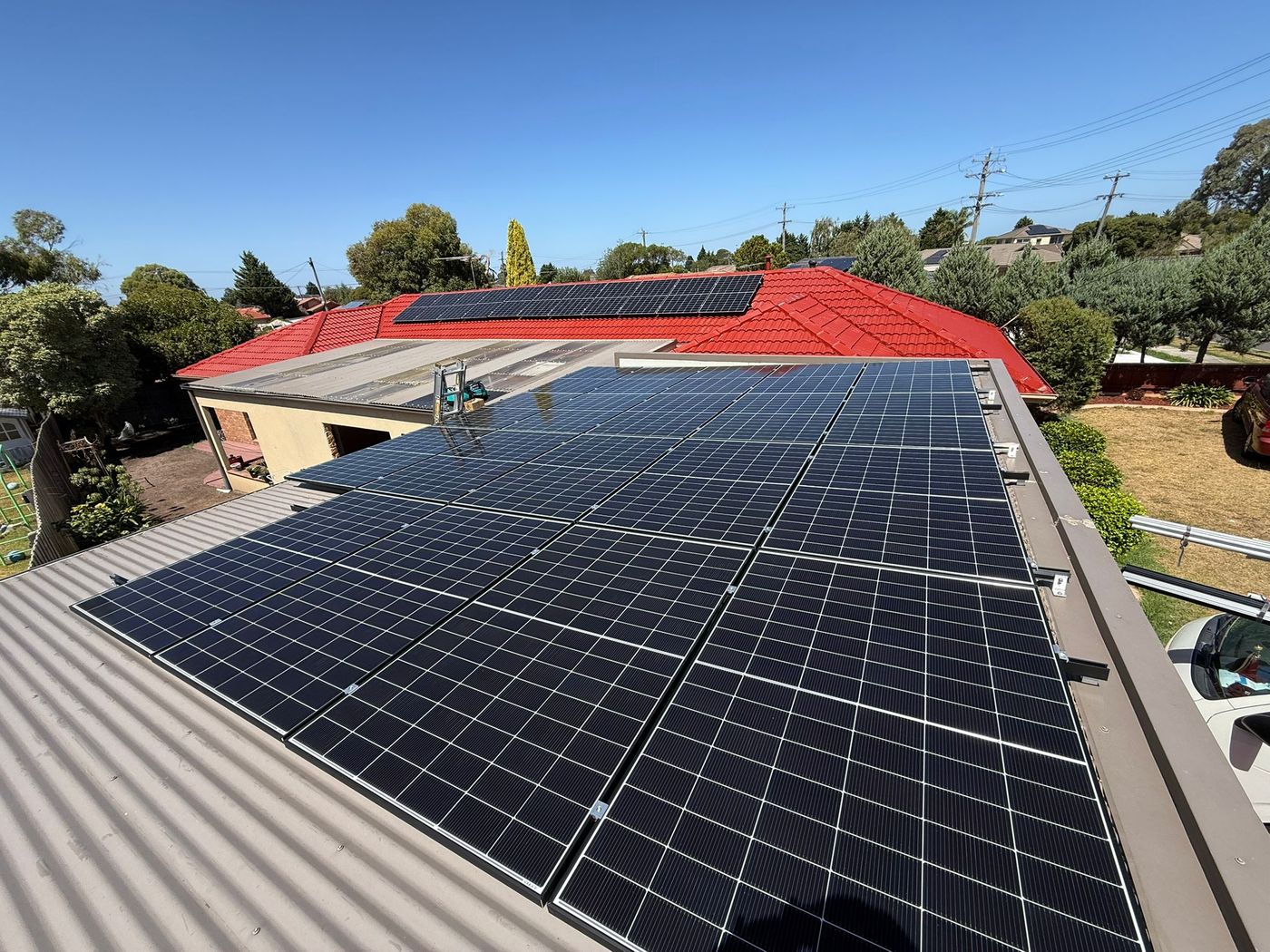 Solar array spanning a tiled roof and a metal extension on the same home